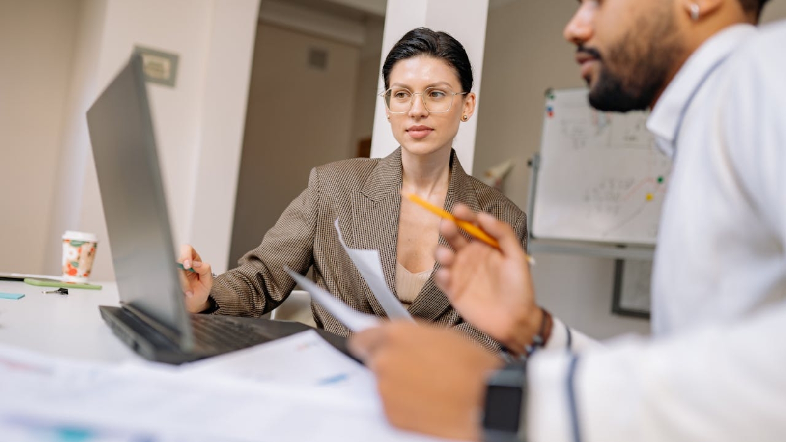 Business professionals collaborating in a modern office, engaged in discussion with technology and documents.